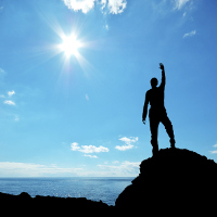Figura de un hombre alzando su brazo derecho en señal de triunfo en la cima de una montaña.