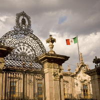 Rejas de un edificio con la bandera mexicana ondeando.