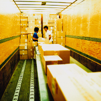 2 trabajadores ordenando unas cajas dentro de un camión.