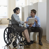 Mujer de negocios en silla de ruedas hablando con un compañero de trabajo