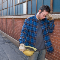 Un hombre con un casco amarillo en la mano con cara de preocupación.