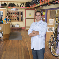 Hombre de brazos cruzados en una tienda de bicicletas.
