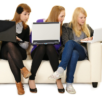 3 chicas jóvenes en un sofá mirando al ordenador de la otra.